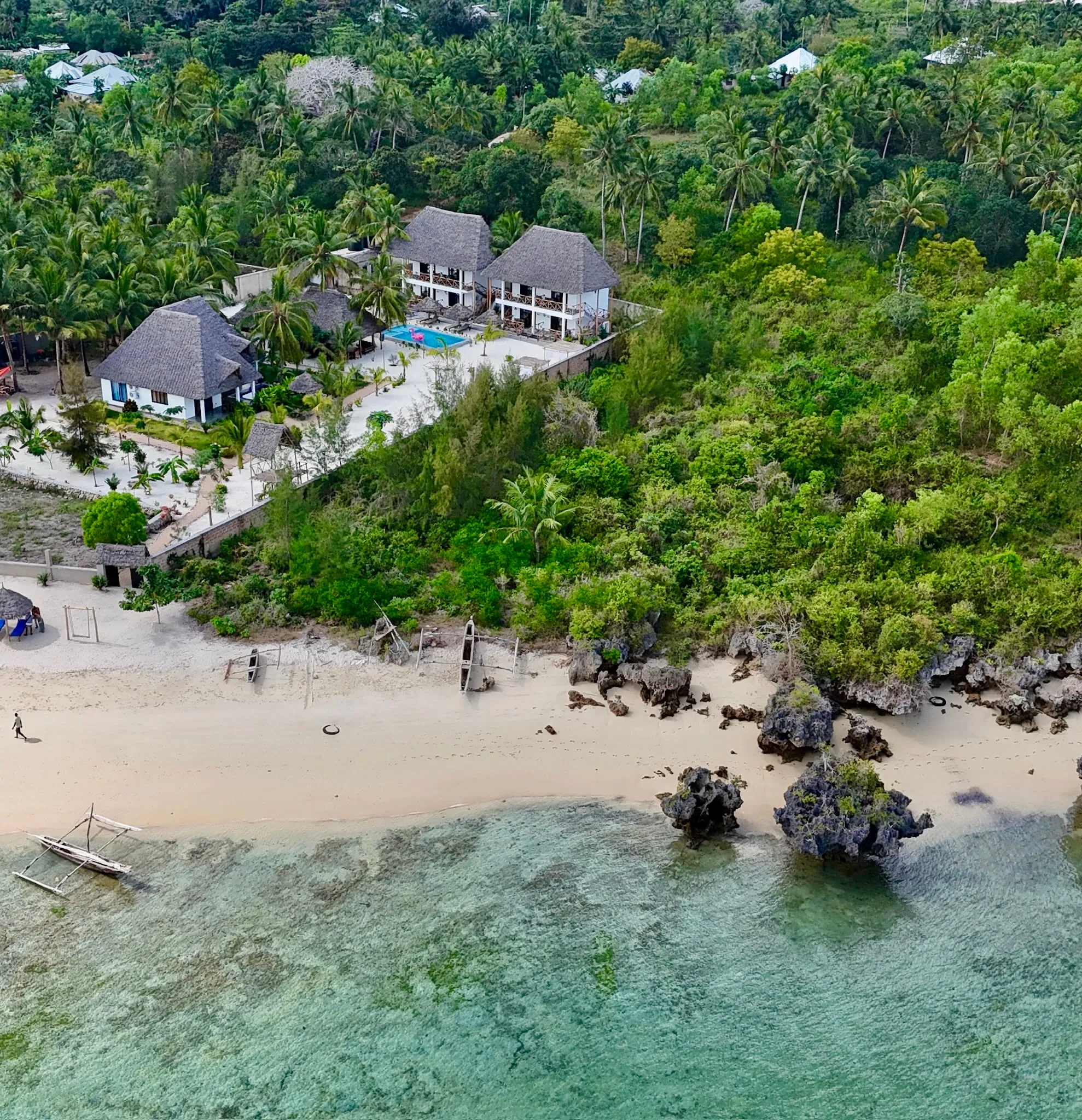 Aerial view of the white sand beach meeting shallow turquoise water and dark reef rock