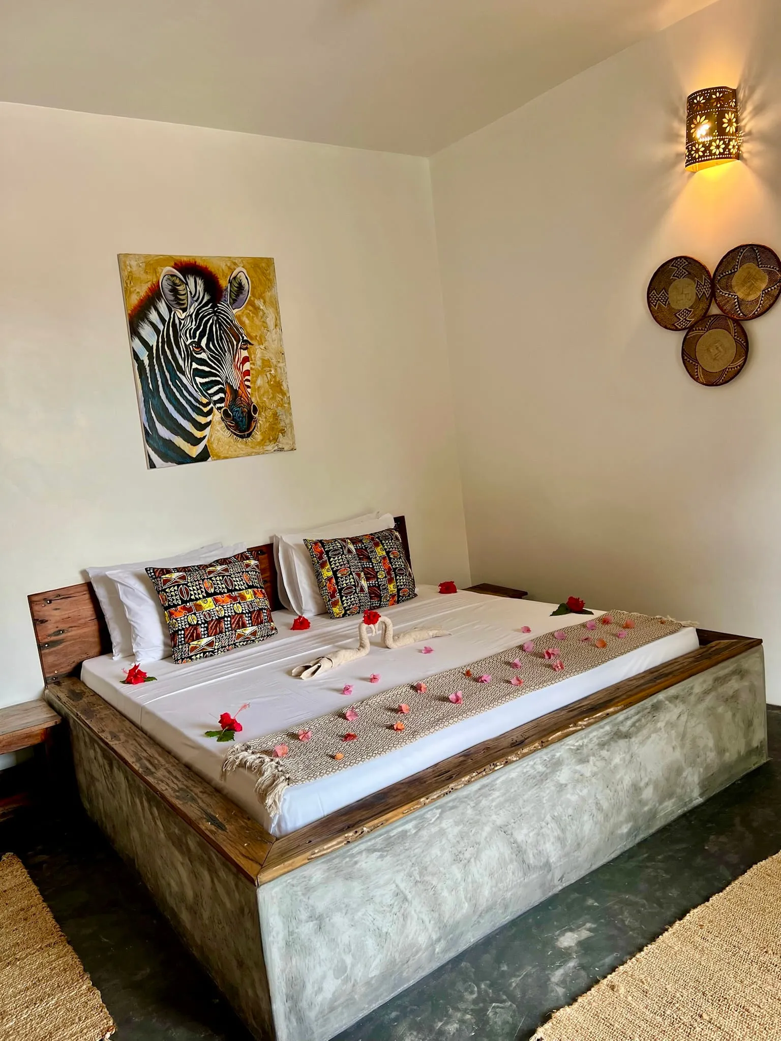 Bed dressed with a towel swan and scattered rose petals