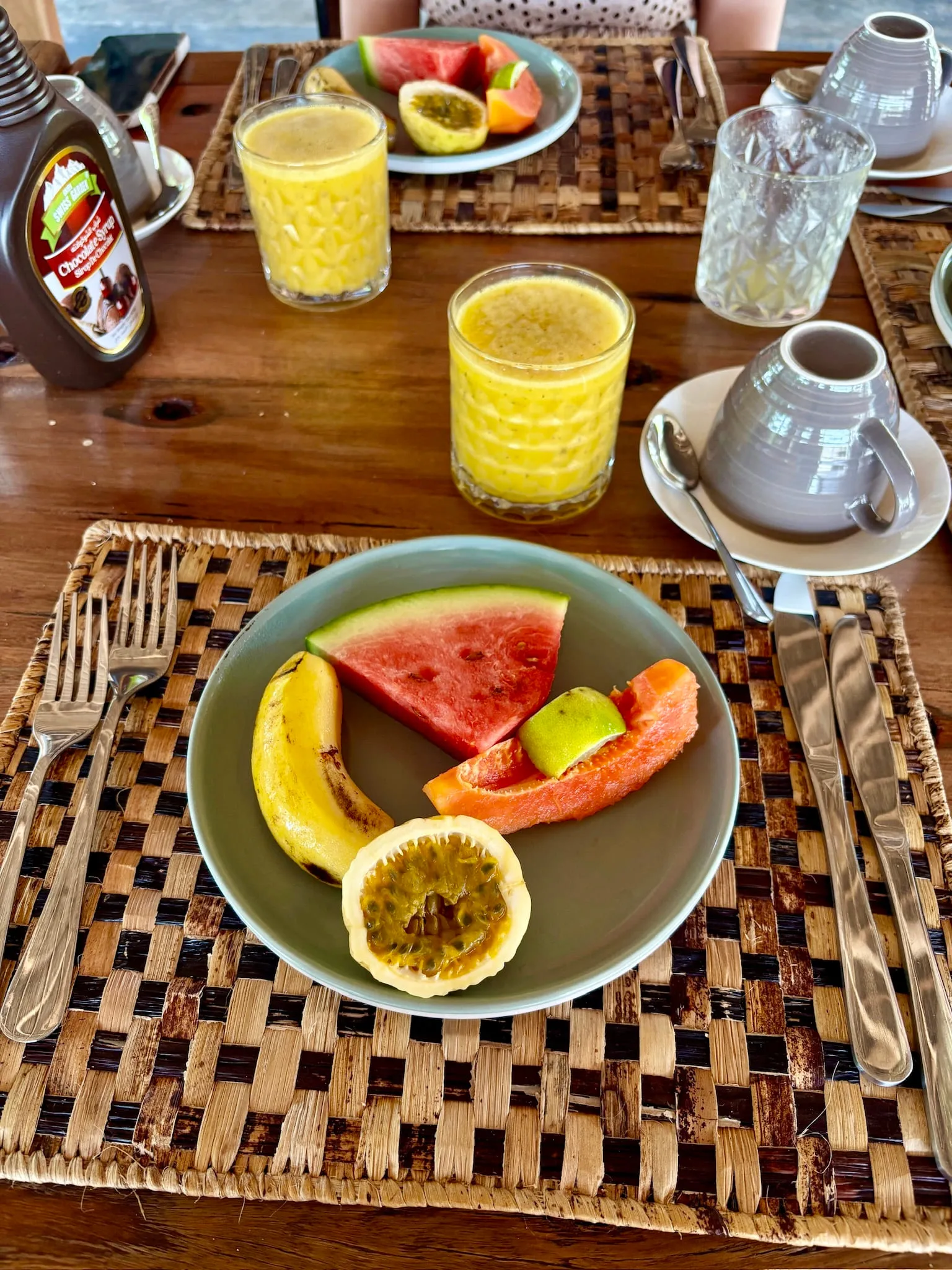 Breakfast of watermelon, passion fruit and papaya with fresh juice and coffee on a woven mat