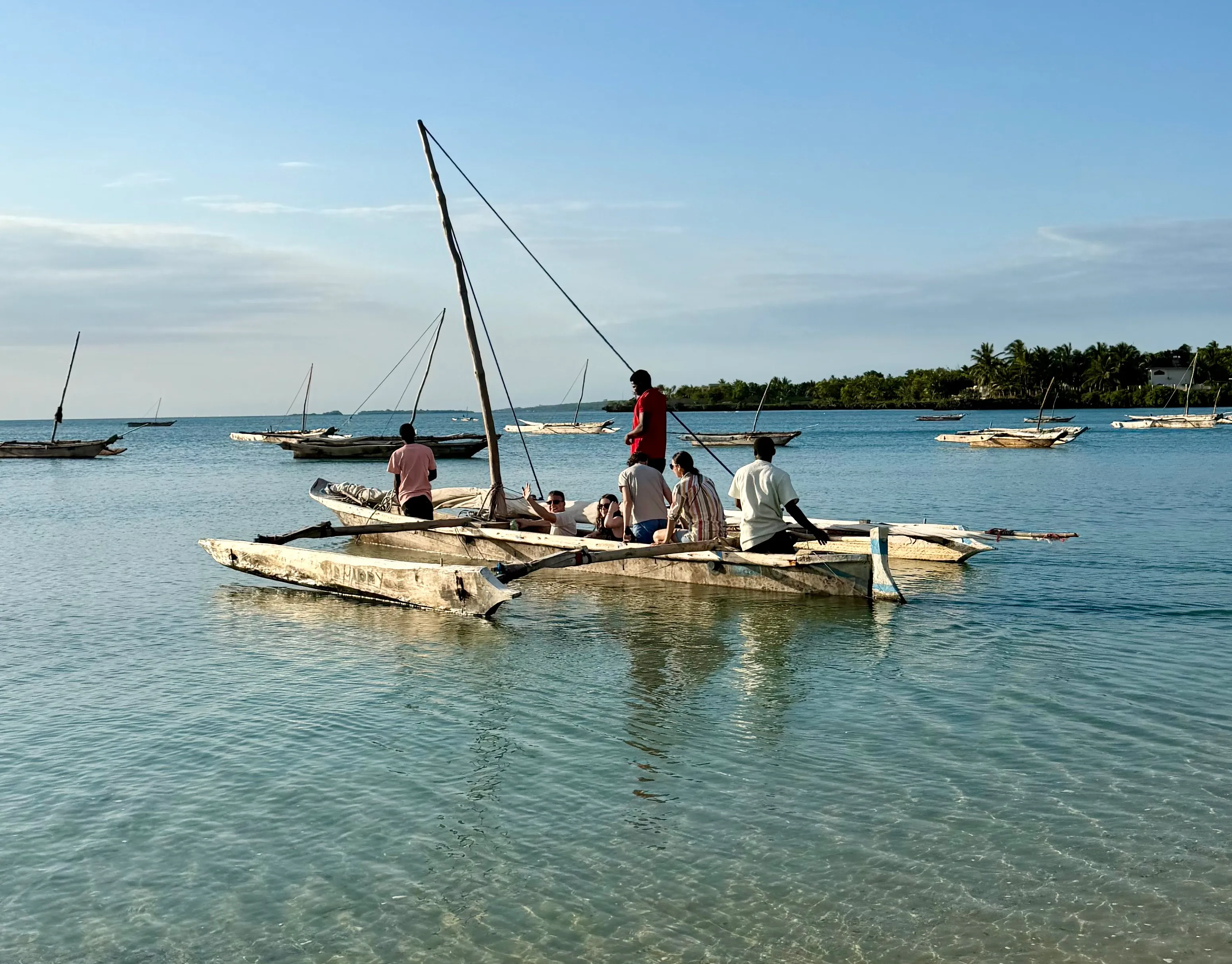 A wooden swing on the white sand beach beside loungers and a thatched umbrella at the water's edge