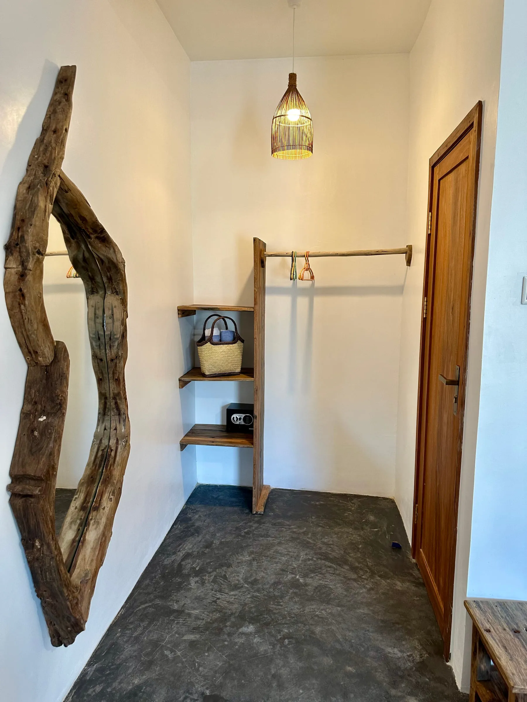 Open dressing area with hanging rail, shelves and a sculptural driftwood piece on the wall