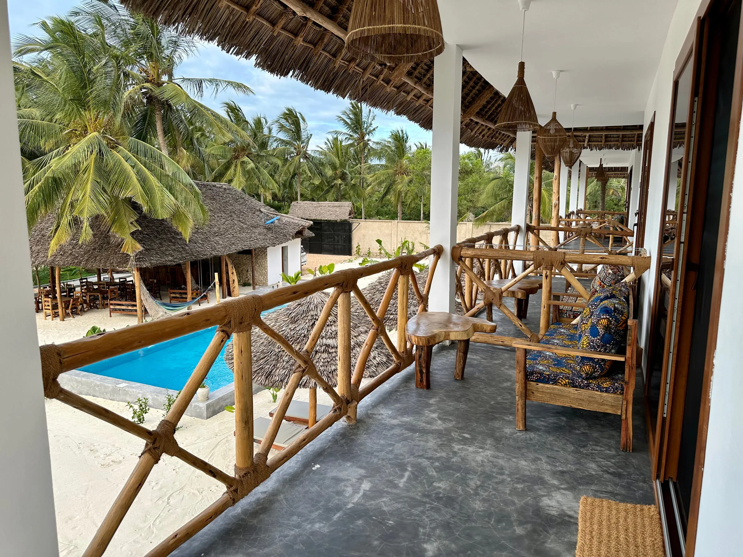 A private terrace with bamboo furniture looking out across the pool and gardens