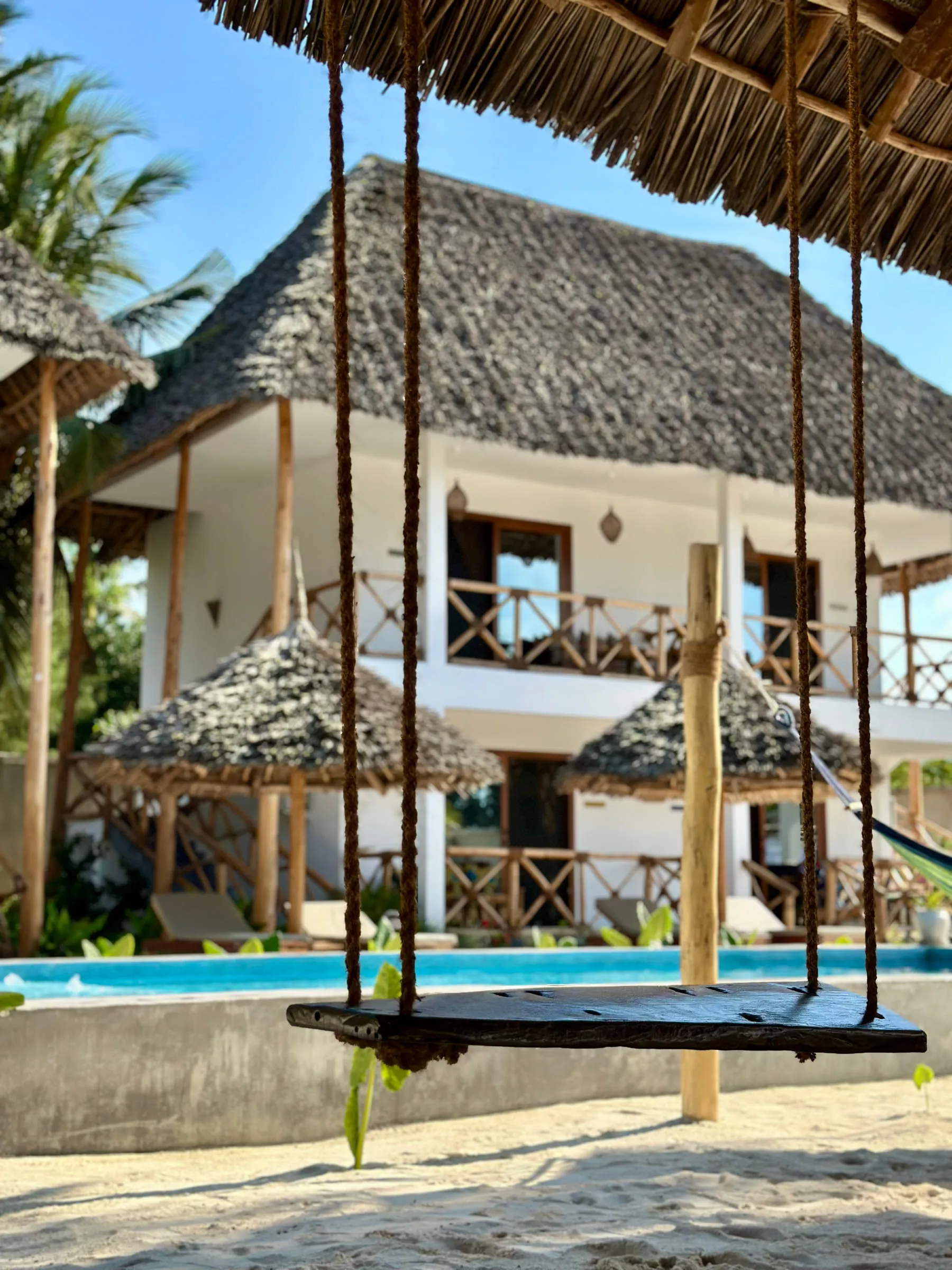 Hanging swing seats under the makuti roof looking out over the pool