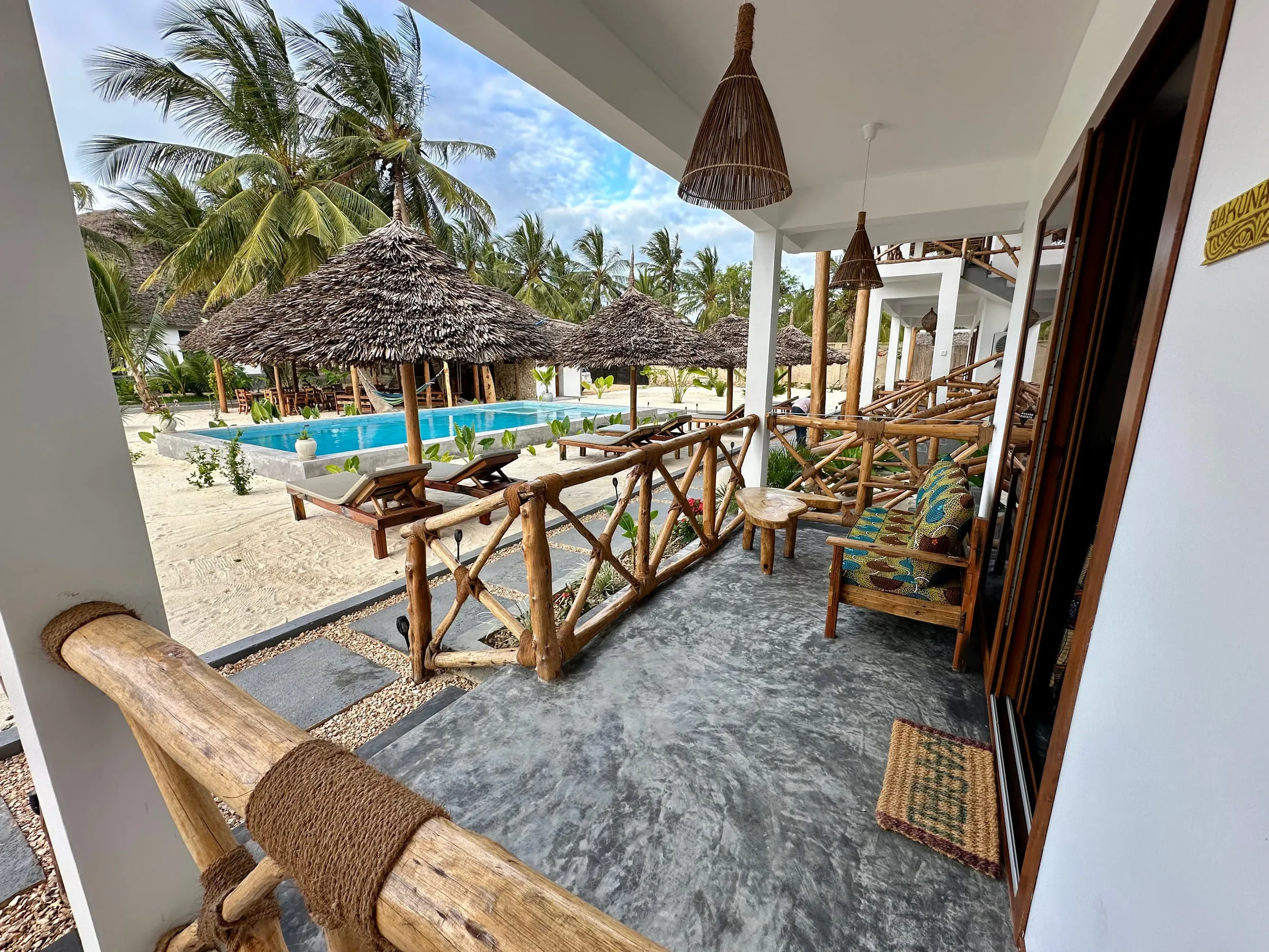 Long shaded first-floor terrace with mangrove pole railings running above the pool