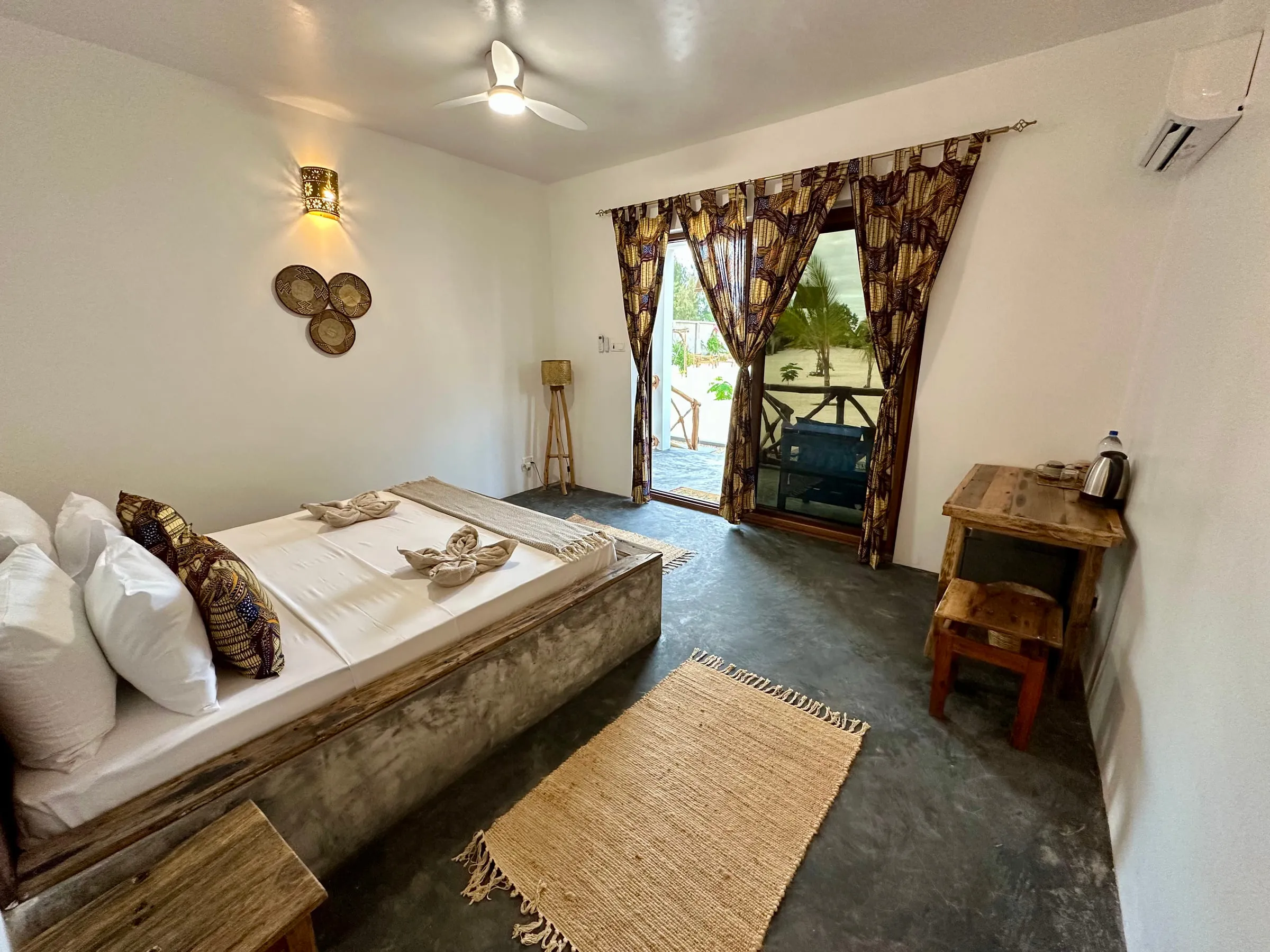Bright bedroom with ceiling fan and curtained doors opening onto a terrace