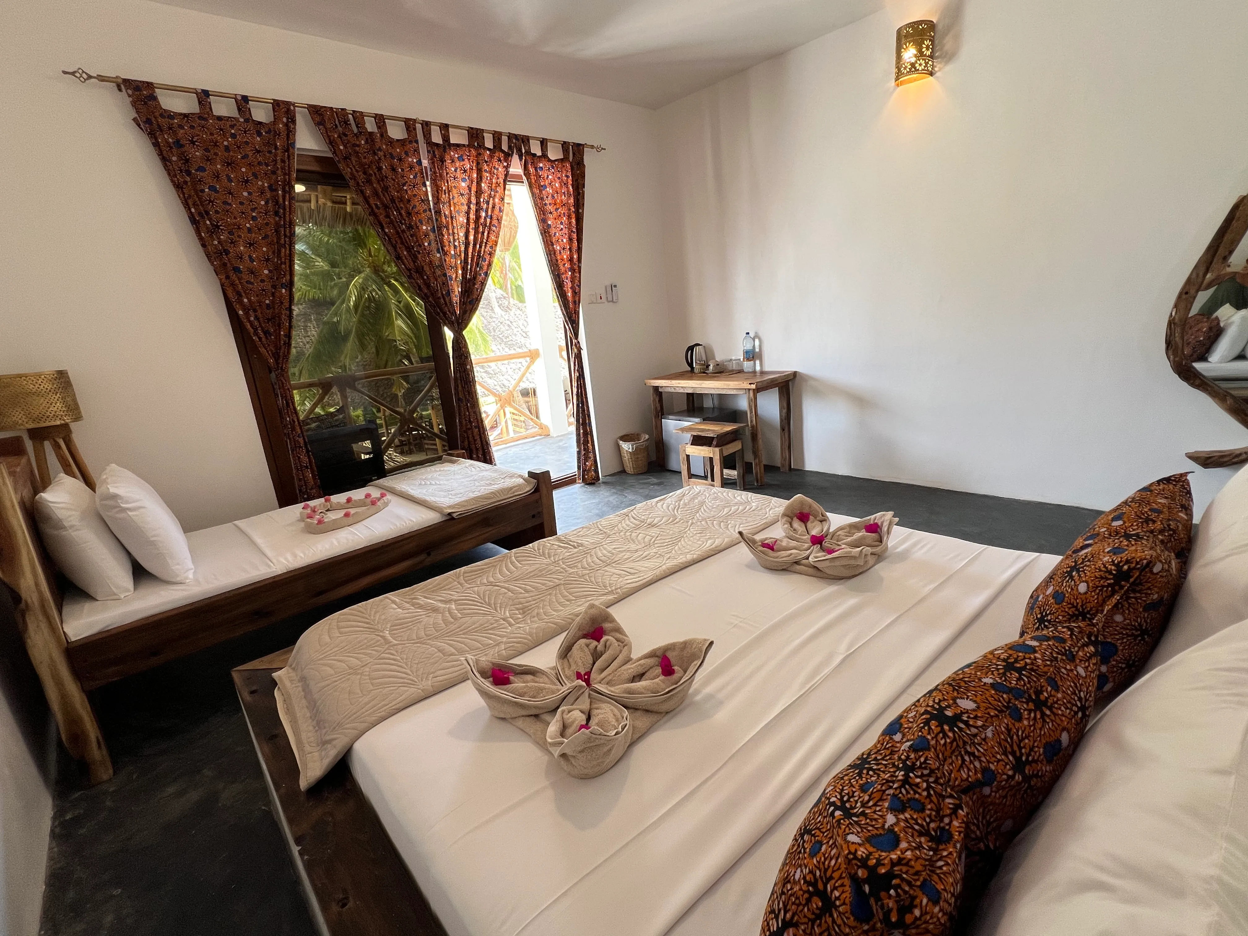 Bright bedroom with a large bed, ceiling fan and curtained doors opening onto the terrace