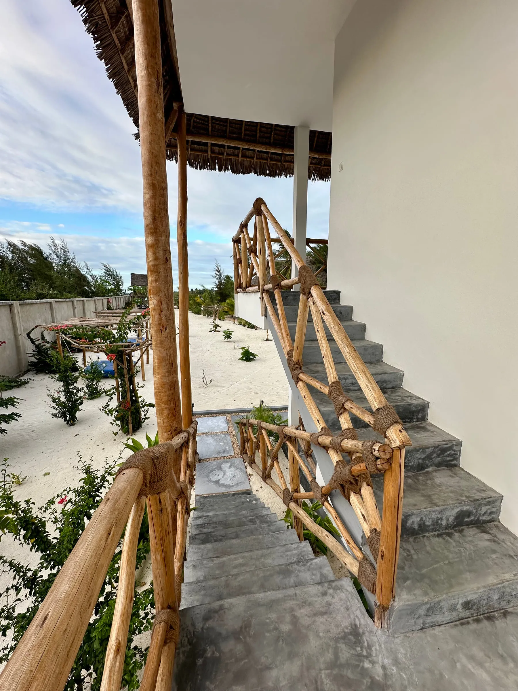 Concrete stairway with hand-tied mangrove pole railings leading up to the first-floor rooms
